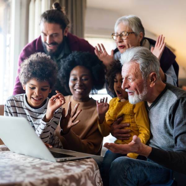 Une famille multi-générationnelle et multi-ethnique devant un ordinateur portable.