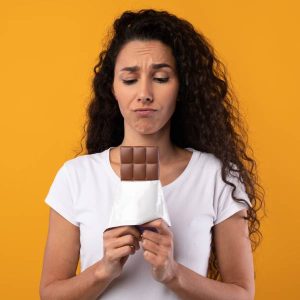 Une jeune femme tient une tablette de chocolat noir dans ses mains s'inquiétant de présence de métaux lourds.