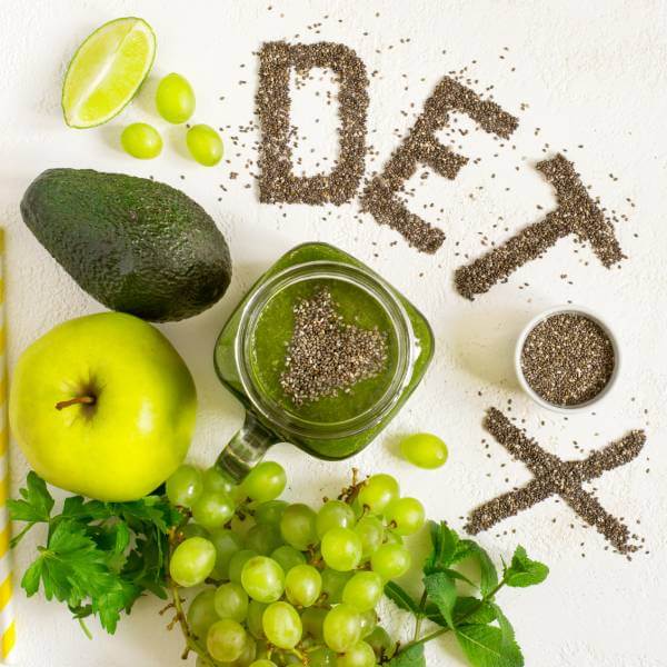 Un assortiment de fruits verts et de graines de chia qui lisent le mot "detox".