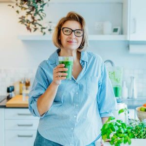 Une dame avec un smoothie de jus vert pour se désintoxiquer naturellement des métaux lourds.