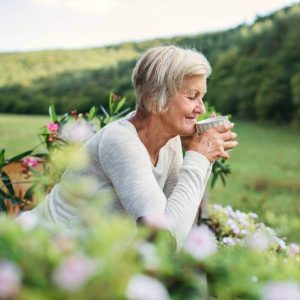 Une dame assise dans la nature boit une infusion de plantes qui absorbent les métaux lourds.