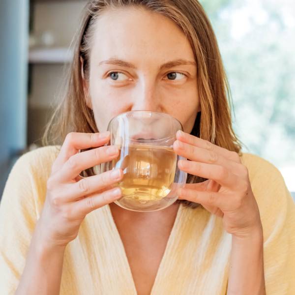 Une jeune femme boit une tisane détox de chardon-Marie et de curcuma.