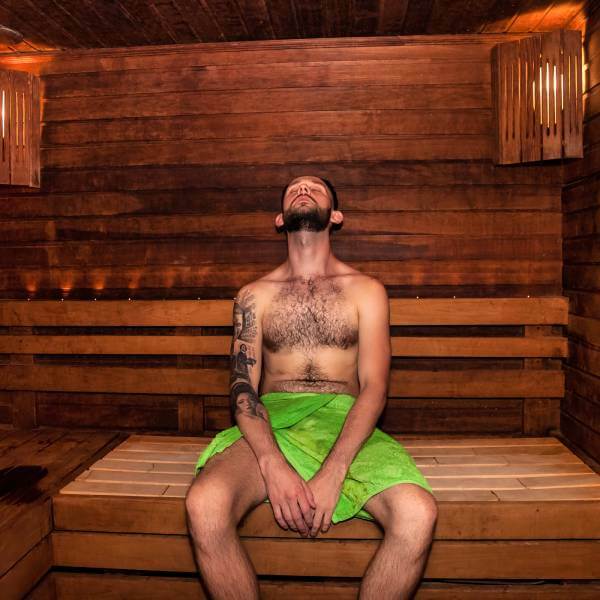 Un jeune homme transpire dans un sauna.