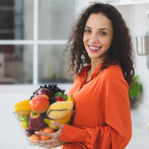 Une jeune femme souriante avec des aliments pour nettoyer son sang.