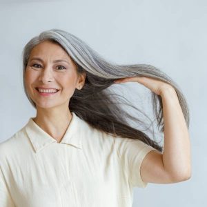 Une dame secoue sa chevelure heureuse des compléments alimentaires pour cheveux qu'elle a choisi.