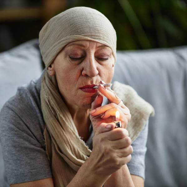 Une femme cancéreuse allume une cigarette.