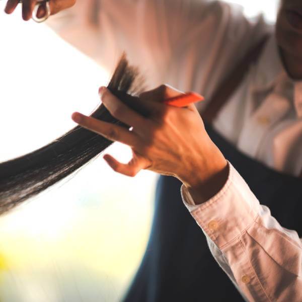 Gros plan sur les mains d'un coiffeur tenant des cheveux.