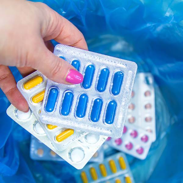 Une main de femme tient des antibiotiques et médicaments.