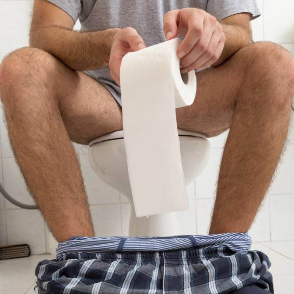 Un homme constipé sur les toilettes.