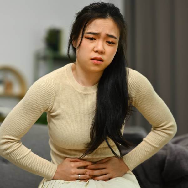 Une jeune femme souffre de maux d'abdomen, un symptome de manque de probiotiques.
