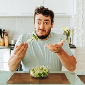 Un jeune homme devant un bol de brocoli se questionne à propos de la maladie de Crohn et l'alimentation.