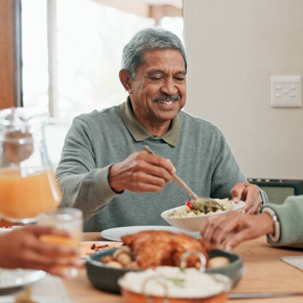 Un homme senior touché par la maladie de Crohn apprécie un bon repas en famille.