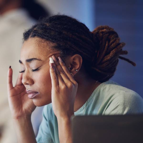 Une jeune femme se masse les tempes pour soulager le stress.